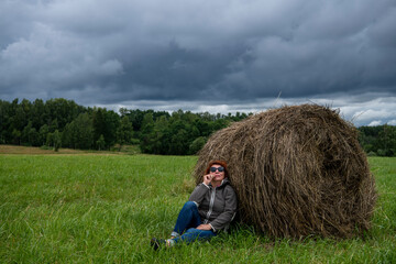 Naklejka na ściany i meble woman resting near a haystack in nature against a gray sky