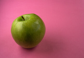 A fresh green apple in a pink background