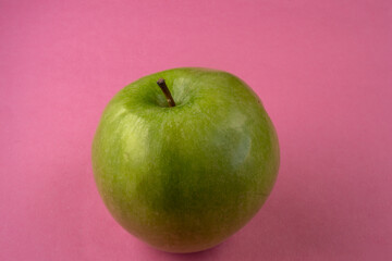A fresh green apple in a pink background