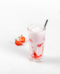Milk cocktail with vanilla ice cream and strawberry juice in a glass on a white background