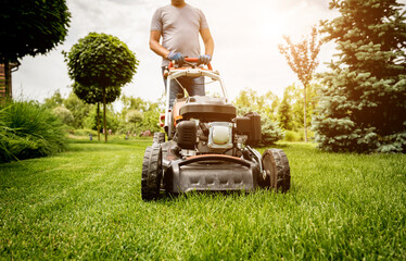 Gardener mowing the lawn. Landscape design. Green grass background - obrazy, fototapety, plakaty