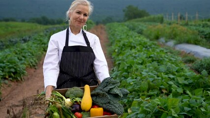 Extreme closeup portrait of woman chef holding a crate of vegetables at sunset or sunrise for farm to table restaurant.