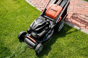 Lawn mower on green grass. Summer garden
