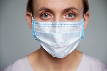 Close up of female doctor or scientist in protective medical mask over grey background