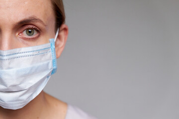 Close up of female doctor or scientist in protective medical mask over grey background