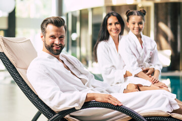 Happy beautiful family in bathrobes are joyful together while sitting in the spa salon
