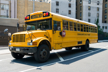 Fototapeta na wymiar Isolated yellow USA american school bus on street in city