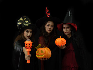 Three attractive young women wearing Halloween costume with scary pumpkin, Jack o Landtern. Cosplay...