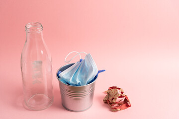 Glass bottle, facemask and gloves into bin and paper ball