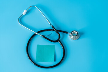 Stethoscope and adshive note on blue background. Medical and health care concept