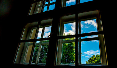 Old window overlooking the blue sky and trees