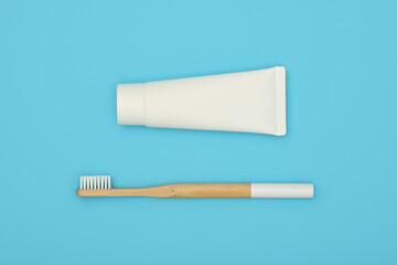 White toothpaste and bamboo toothbrush on blue