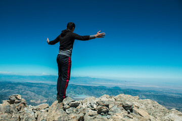 a man stands on the top of a mountain with open arms