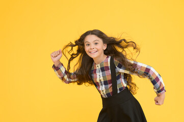 Extremely effective product. Child with natural beautiful healthy hair yellow background. Tips for healthy hair. Towards the wind. Girl kid long hair flying in air. Growing hair. Natural beauty