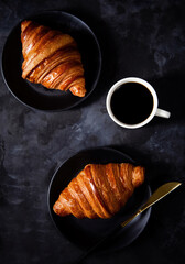 Two Croissant,dinner knife and coffee on dark background.