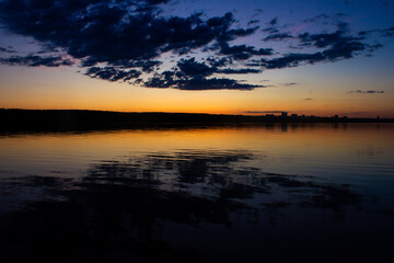 Very beautiful blue-gold sunset on the river. Fluffy clouds reflected in the water