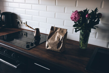 Craft bag, coffee cezve and flowers on the kitchen table.