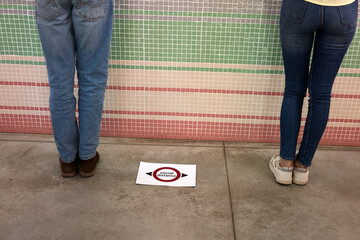 COVID-19 coronavirus. supermarket message asking customer to keep distance. photo of feet standing in public space practicing social distancing