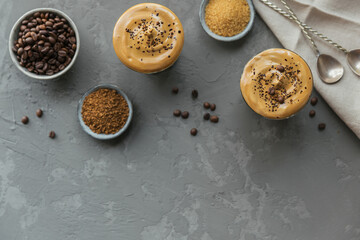 Dalgona whipped coffee, instant, cream, iced coffee. Cocktail with coffee, milk and ice cubes on grey background mockup. Trendy drink background with copy space for text.