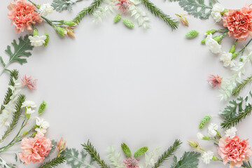 Fototapeta na wymiar White and coral flowers and silver-green leaves on pastel grey background. Flowers composition with copy space, flat lay.