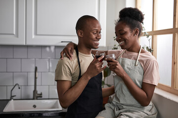 african american newlyweds drink wine while cooking, happy together in the kitchen, have rest, spend time with each other, smile and talk