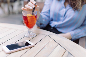 Cropped shot of woman relaxing and drinking fresh summer cocktail on the terrace of cafe. Summertime concept.