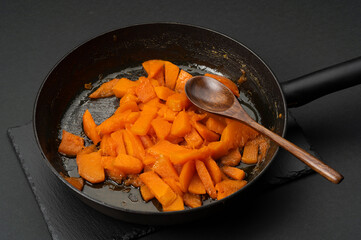 Braised pumpkin with honey in a pan on a black background