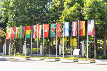 State flags of different countries on flagpole in a row waving in the wind