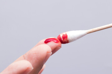 Use a cotton swab to wipe the blood at the wound on fingertips that are bleeding on white...