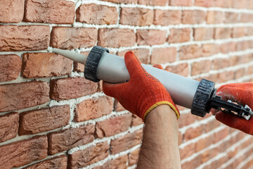 Applying grout with a syringe. Grouting decorative tile with white cement grout. - obrazy, fototapety, plakaty