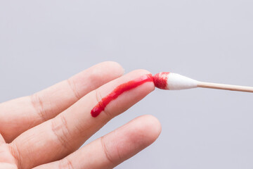 Use a cotton swab to wipe the blood at the wound on fingertips that are bleeding on white...