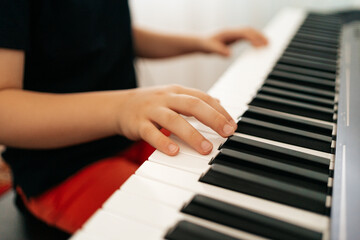 Fototapeta premium Close up young boy hands on digital piano. Playing keyboard, focused kid have activity at home. Hobby