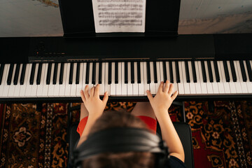 Young boy sitiing at digital piano. Playing keyboard, focused kid have activity at home. Hobby