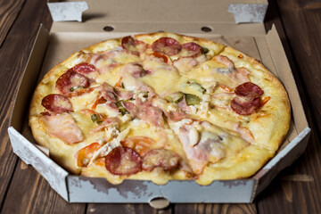 pizza in an open cardboard box on a wooden table.