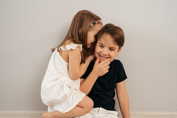 Girl whispers boy in the ear a secret. Childrens gossip