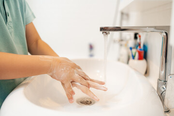 Hands of kid At bath Washing hands with soap under the faucet with water. Clean and Hygiene concept.