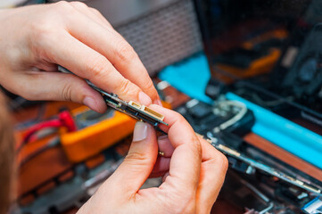 A professional system administrator holds the power supply sockets in his hands. A man repairs and builds a computer.