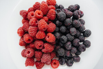 Black and red raspberry close-up on a white background. Healthy food, natural vitamins. Fresh berries