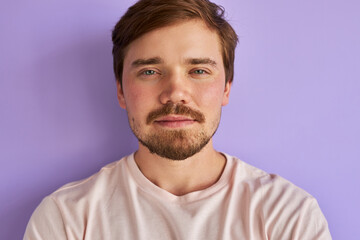 Obraz premium portrait of mysterious caucasian man isolated over purple background, handsome calm guy is in contemplation