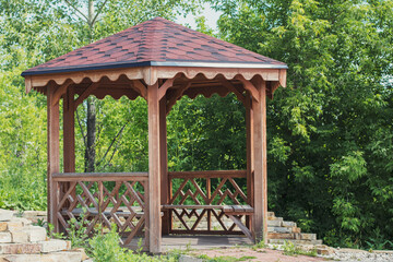 Beautiful gazebo made of wood with carved railings in the park. Landscape on a summer day with...
