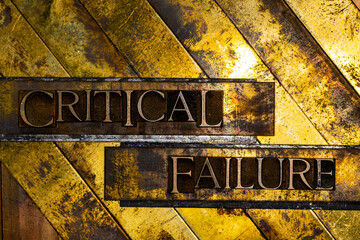 Critical Failure text formed with real authentic typeset letters on vintage textured silver grunge copper and gold background