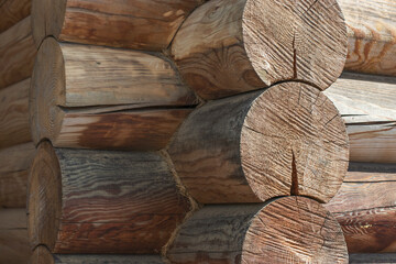 Part of the wall of a house in the Russian style made of wooden round logs. Construction of buildings from ecological materials.