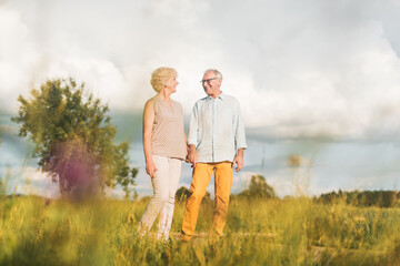 Senior husband and wife having a walk in summer landscape