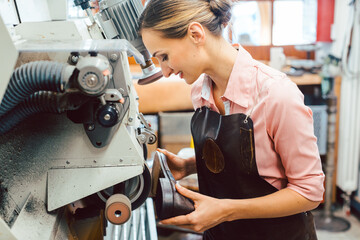 Woman cobbler working on machine in her shoemaker workshop
