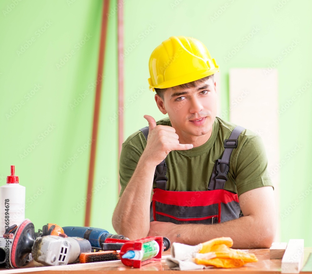 Wall mural Young man carpenter working in workshop