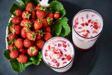 Strawberry milk smoothie in glass on a dark background