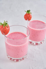 Two glasses with strawberry shake on white background