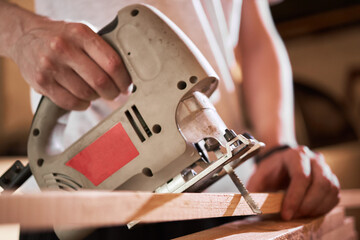 caucasian male person work with wood at his garage or workshop. wood craft concept. carpenter housework concept. wooden furniture craft at domestic life.