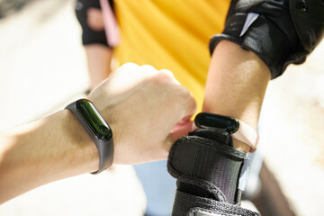 female person touching smart watch or fitness tracker while roller skating leisure activity. close up. sunny day. girl wearing hand protection for sport exercises.