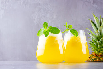 Pineapple juice on a gray background. Juice for detox in the glass. Pineapple smoothie with fresh pineapple. Healthy summer drink with mint